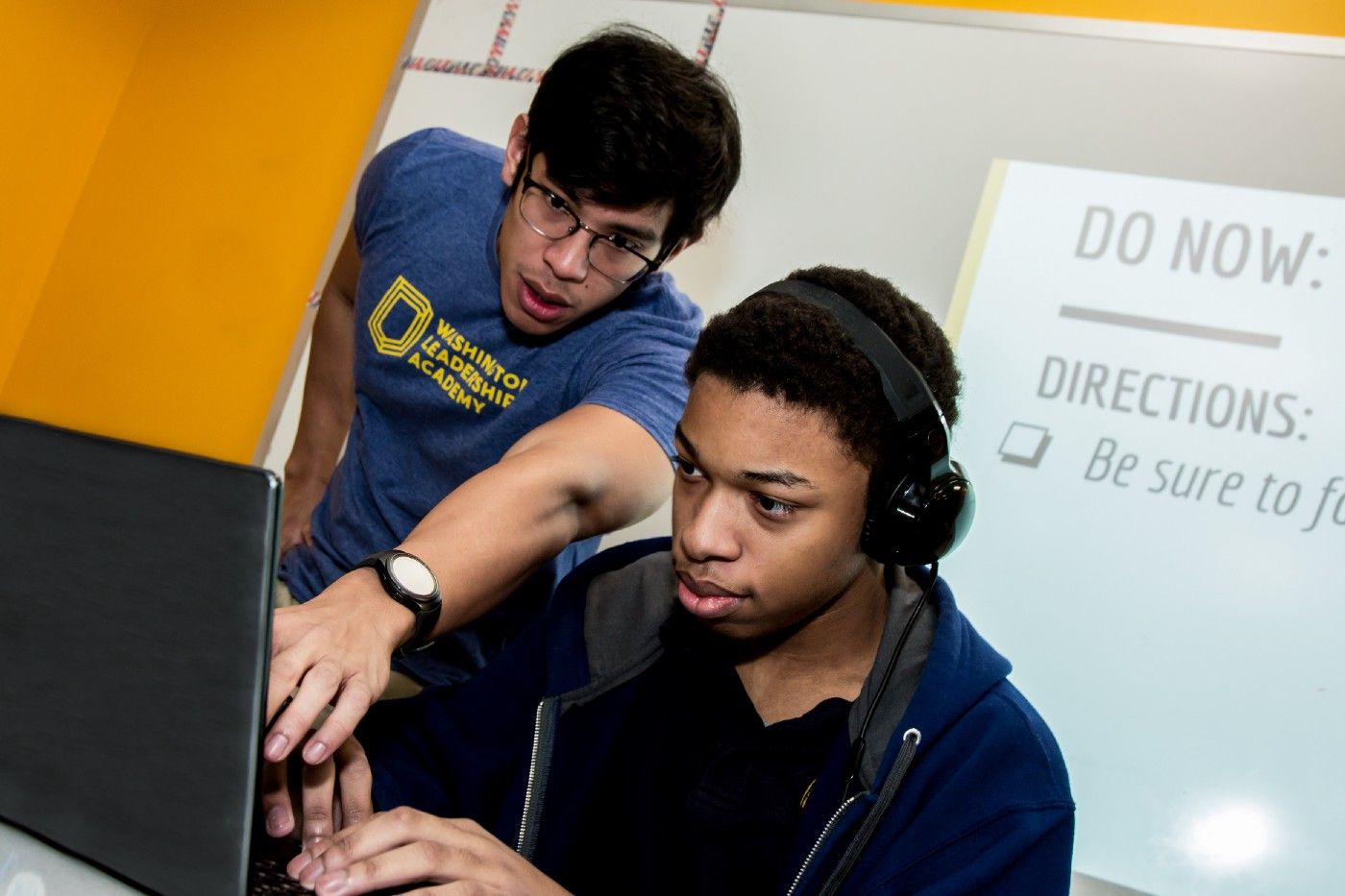 Two students collaborating on a laptop.