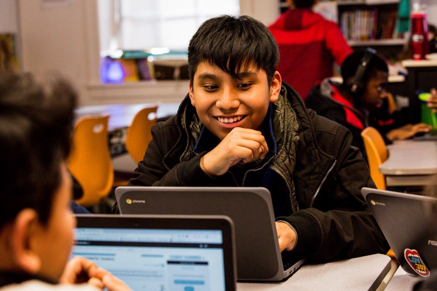 A student smiling at his laptop.
