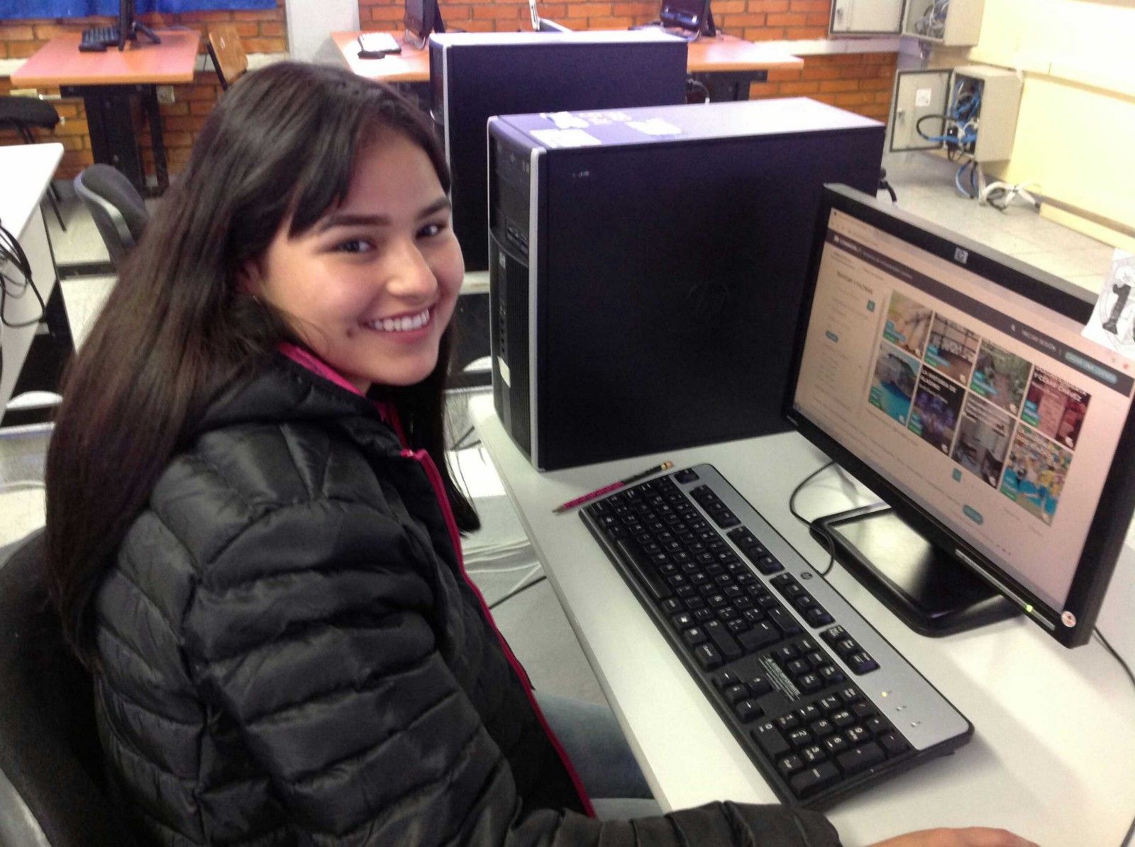 A student smiling at the camera and browsing the CommonLit Español library. 