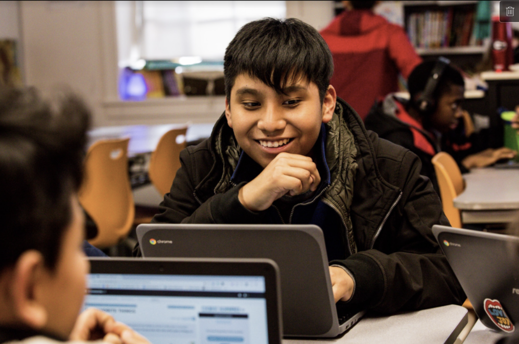 Student looks at a CommonLit reading lesson on his laptop, smiling.
