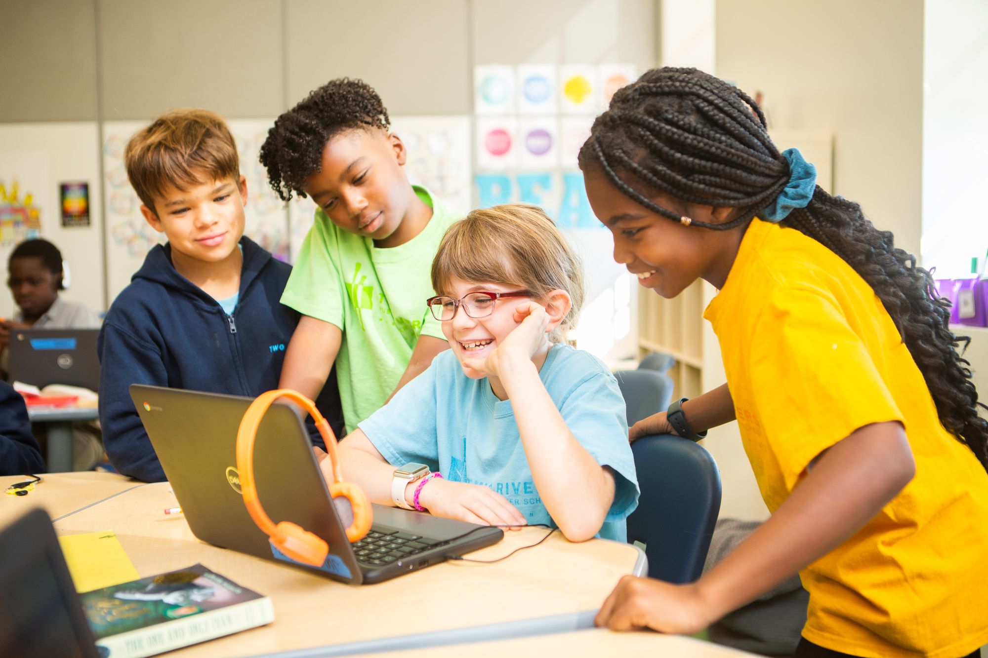 Four students gathered around a computer smiling.