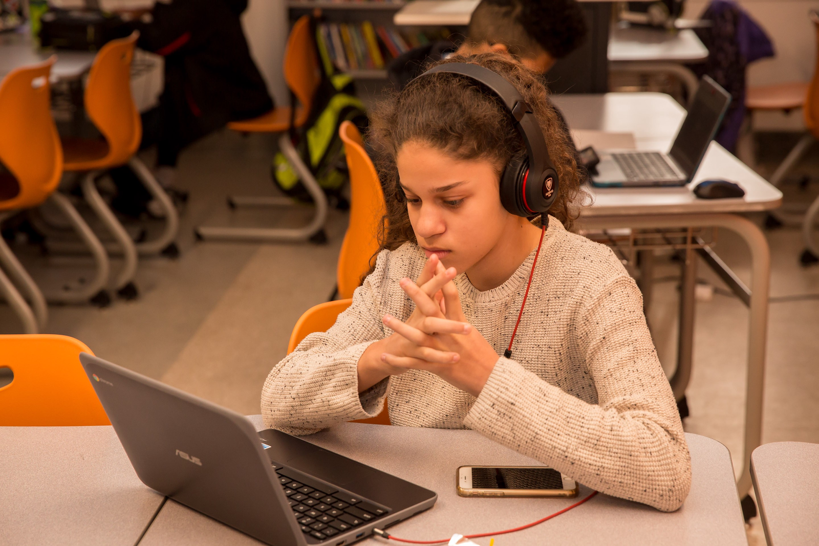 A student with headphones listens to a CommonLit text read aloud. 