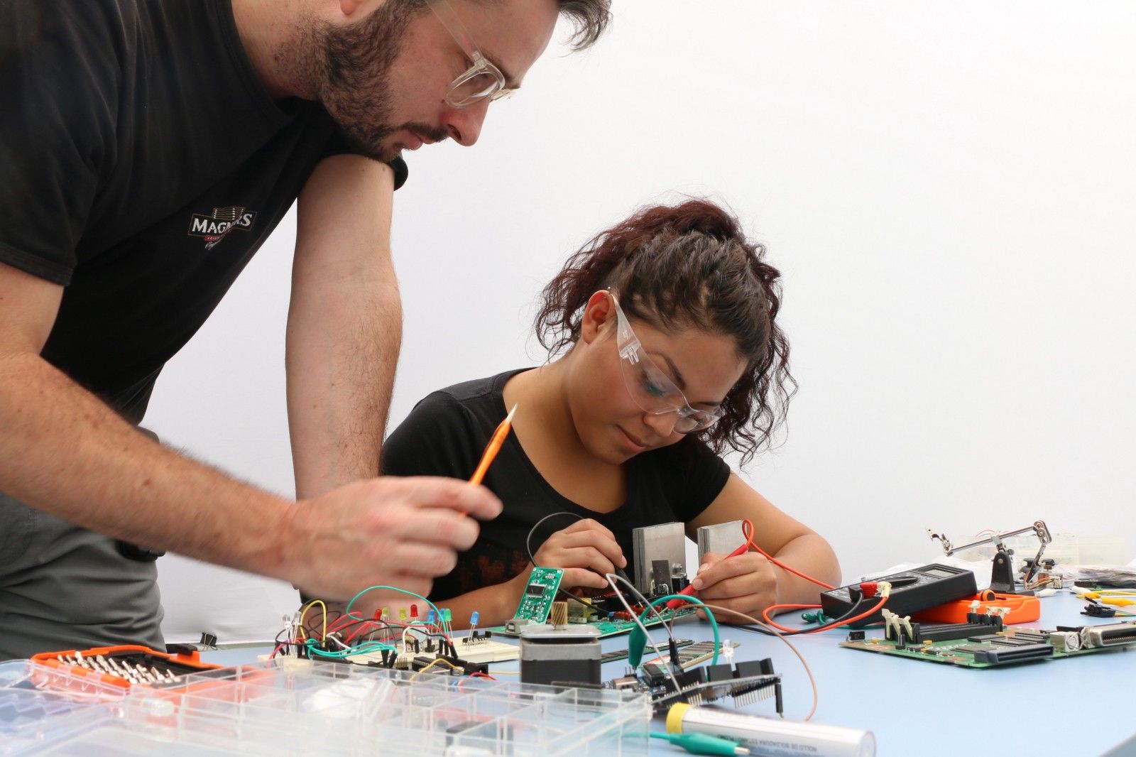 Un maestro y una estudiante creando algo con cables y piezas.