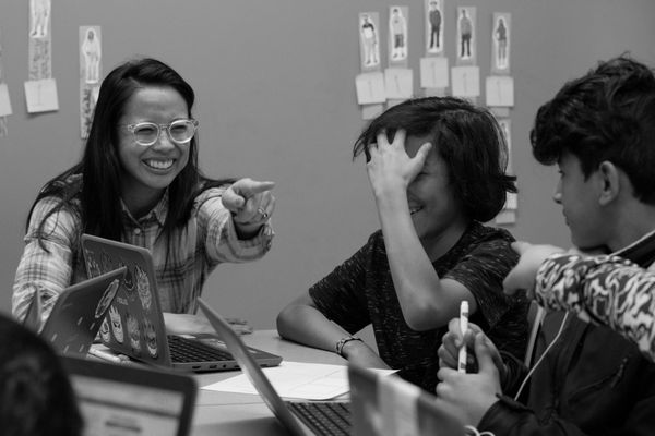 Black and white photo of students and teacher laughing.