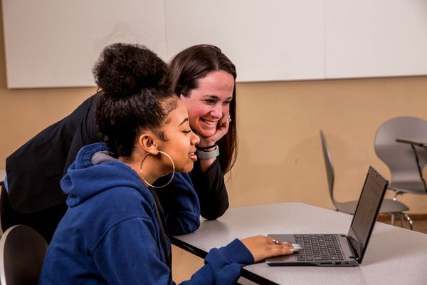 Teacher and student work together on a computer.