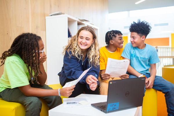 Four students gathered around a computer and smiling.